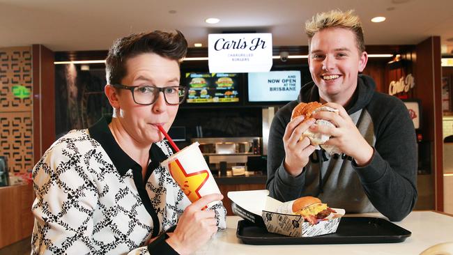 Kylie Lawrence and Jordan Roberts try a Carl's Jr. meal at Brisbane Airport. Picture: Claudia Baxter