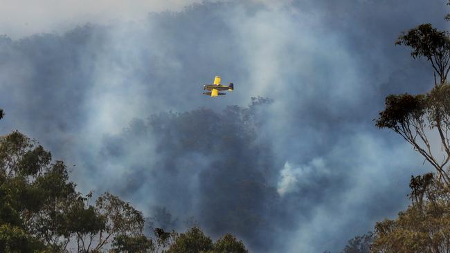 A light plane waterbombing to make sure the Lower Beechmont fire containment lines hold in the high winds. Picture: Glenn Hampson