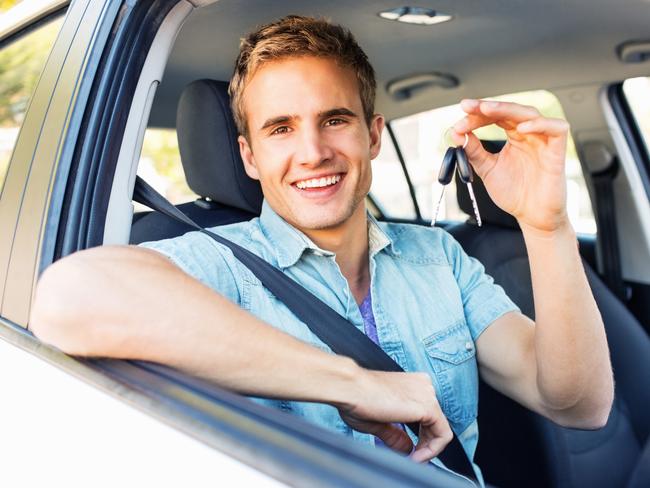 Portrait of happy young man showing new keys while sitting in car. Horizontal shot.