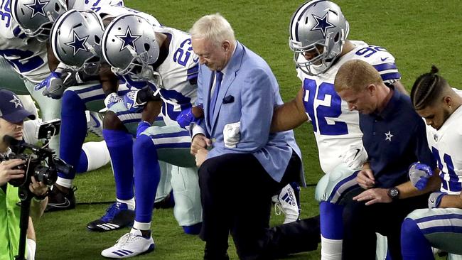 Dallas Cowboys owner Jerry Jones joins his players in kneeling before the anthem in Arizona yesterday. They then stood and linked arms for the anthem.