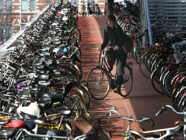 A woman manoeuvres her bicycle on one of the decks of a bicycle parking station in Amsterdam. The Dutch capital and other European cities started to embrace cycling after the oil shocks of the 1970s. Could coronavirus cause a similar rise in popularity for cycling in Australia? Picture: AP Photo/Peter Dejong