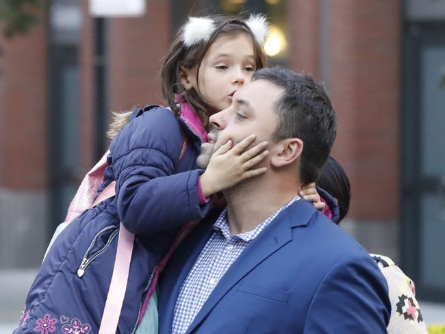 A relieved parent comforts his daughter after school pick-up. Picture: Reuters