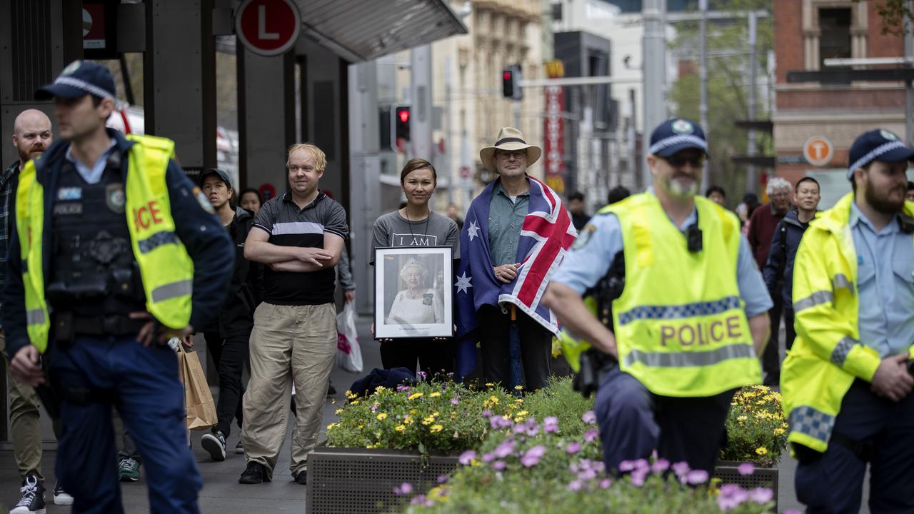 Three pro-monarchy supporters stand behind police in Sydney. Picture: NCA NewsWire / Nikki Short