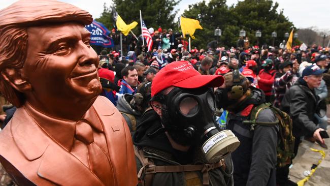 A Trump supporter wears a gas mask and holds a bust of him after he and hundreds of others stormed the Capitol building on January 6.