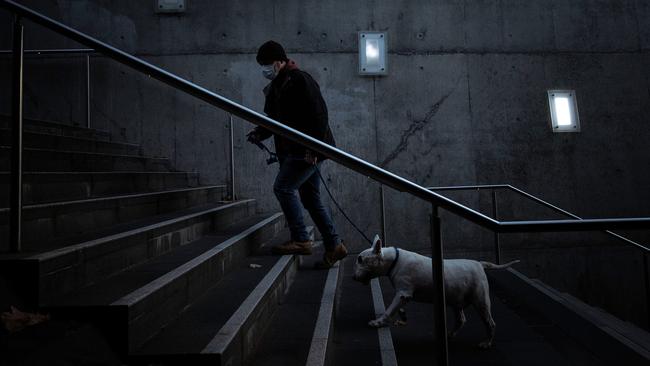 A man wearing a mask walks his dog at Southbank in Melbourne. Picture: Darrian Traynor/Getty