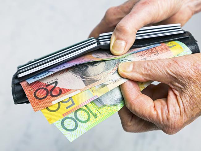 AUSTRALIAN CURRENCY/ DOLLARS/  PICTURE: istock Close-up, senior female hands taking Australian banknotes (cash, currency) from purse containing many credit cards.  Horizontal, studio, copy space.