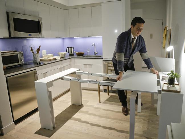 Stage 3 Properties co-founder Christopher Bledsoe demonstrates a desk that expands into a dining table that can seat up to 12 people. Picture: Julie Jacobson