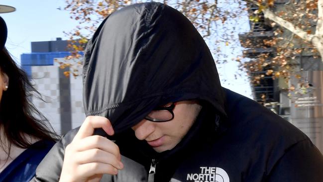 Brenton Skanes, 18, uses his jacket hood to cover his face as he leaves the Adelaide Magistrates Court on Friday. Mr Skanes is charged with importing the largest quantity of LSD tabs ever seized in South Australia. Photo: AAP Image/Sam Wundke.