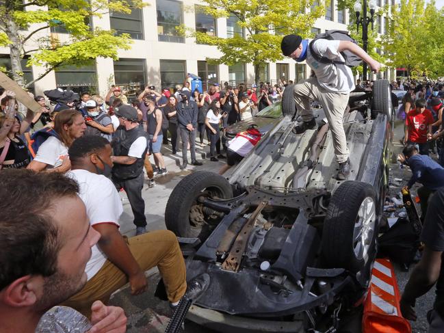 Protesters flip a vehicle over before burning it in Salt Lake City.