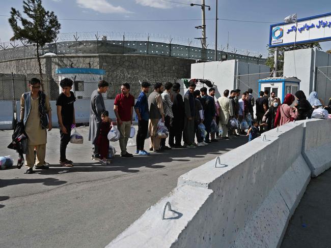 Afghans, hoping to leave Afghanistan, queue at the main entrance gate of Kabul airport in Kabul on August 28. Picture: AFP