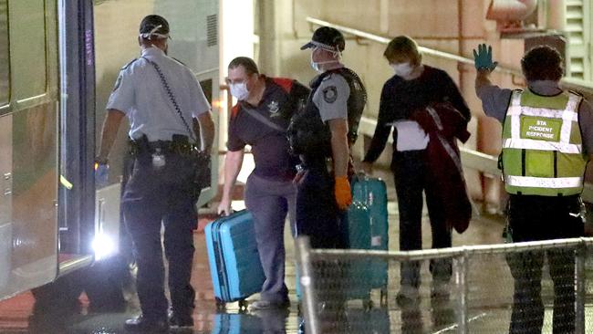 Passengers arriving at Sydney’s international terminal last night are met by a bus to be taken to a hotel for enforced 14-day isolation. Picture: Damian Shaw