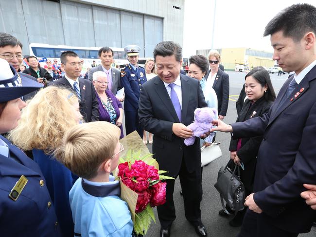 President Xi is given gifts of Bobbie the lavender bear and red peonies by students Olivia Neubauer, 10, from Albuera Street Primary School, and Louis Watson, 9, from Waimea Heights Primary School. Picture: NIKKI DAVIS-JONES