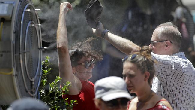 Spectators cool down in front of water spraying fans as temperatures rise close to 40 degrees at Melbourne Park. Photo: AP