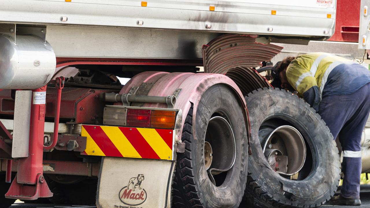 A heavy haulage tow operator checks the damaged wheels of the truck involved in a fatal crash on the Warrego Hwy near Bowenville. Picture: Kevin Farmer