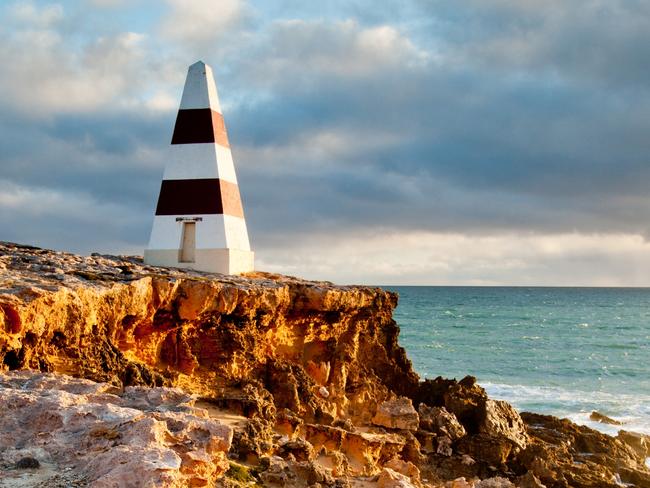 Robe Obelisk with stormy clouds and sun setting on cliffs and rocky coastline, Limestone Coast, South East, South Australia. Picture: Getty Images