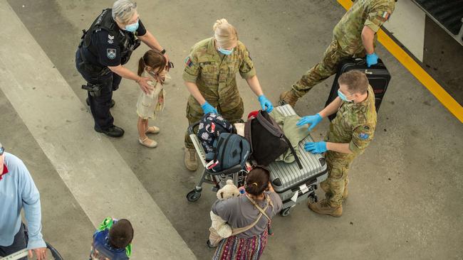 Welcome to Queensland .... A family is processed at Brisbane Airport before being taken to hotel quarantine. Picture: Brad Fleet