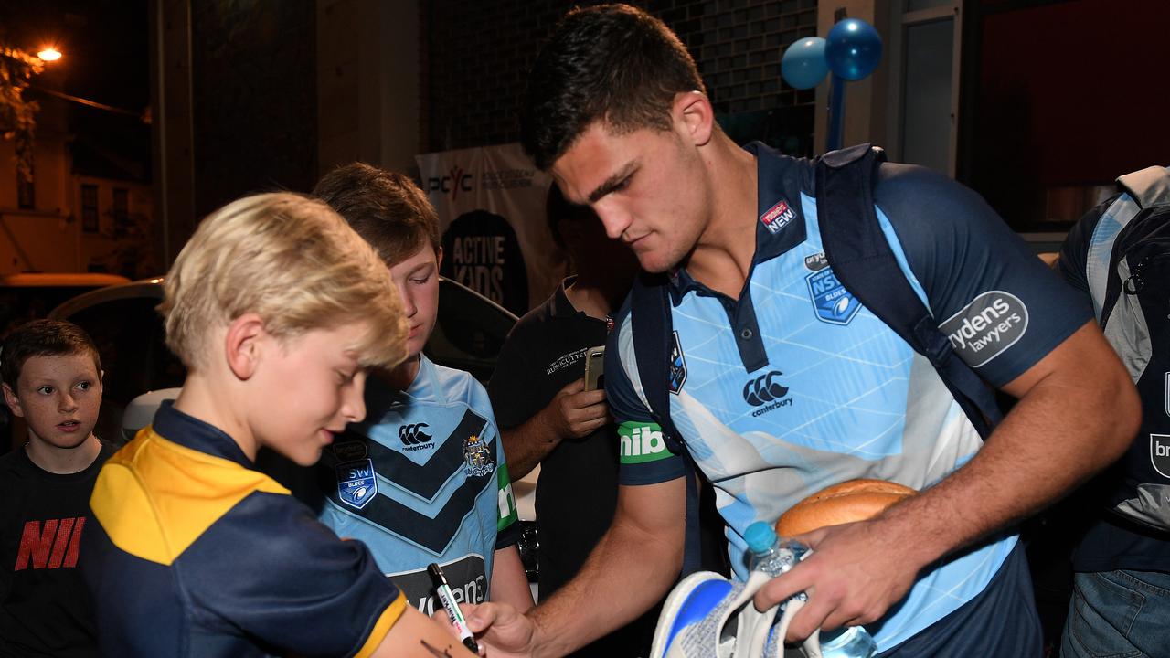 NSW Blues State of Origin player Nathan Cleary signs an autograph on the arm of a young fan.