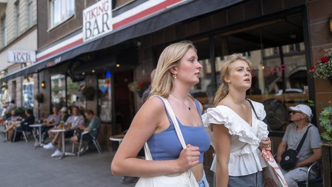 Julia Carlsson and Ellika Wohlfeil walk past a busy bar in Stockholm, Sweden. Picture: Getty Images