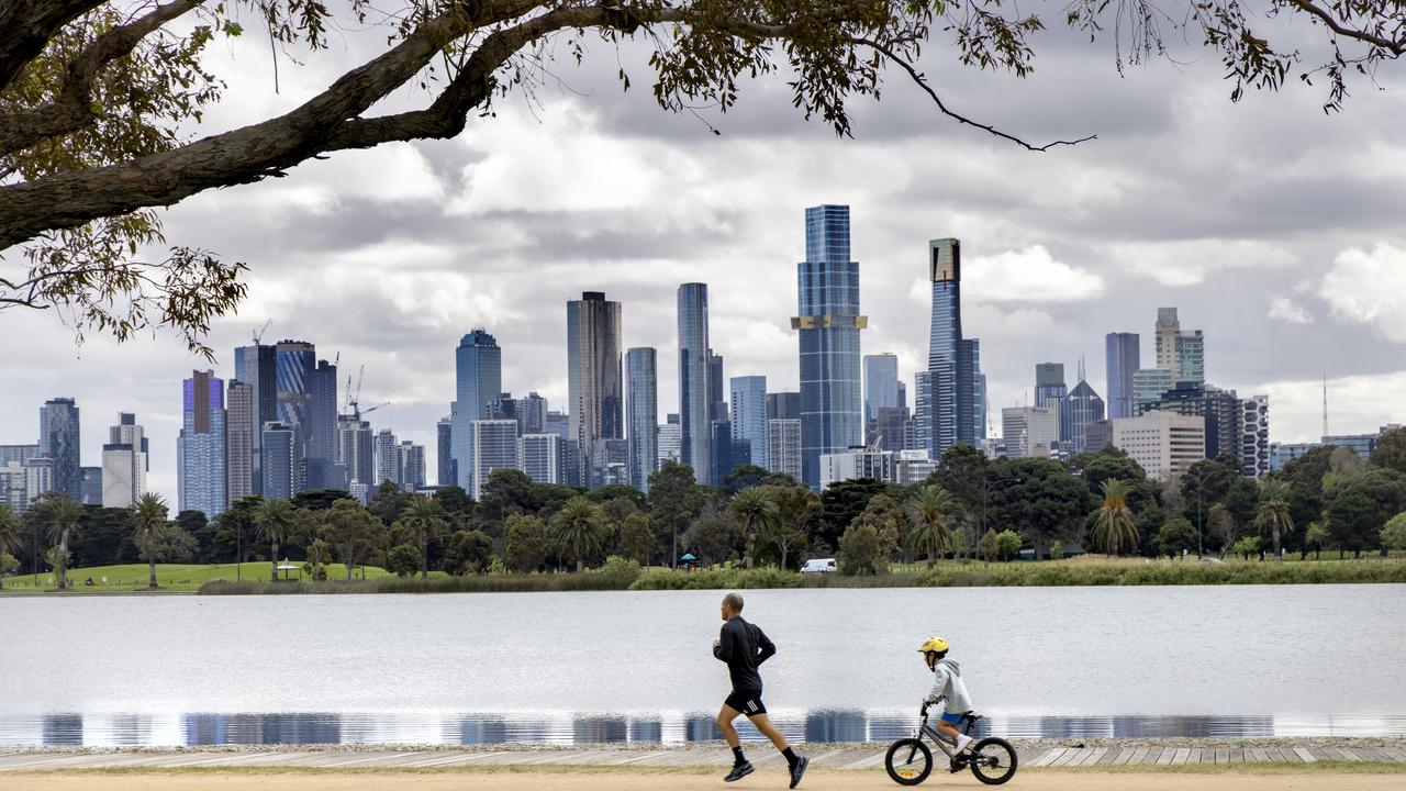 A man runs while his son cycles around Albert Park Lake in Melbourne