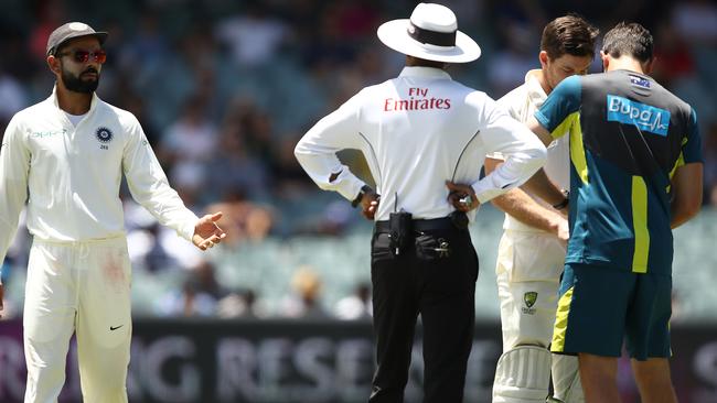 Virat Kohli has words with the umpire as Tim Paine receives treatment for a hand injury. Picture: Getty