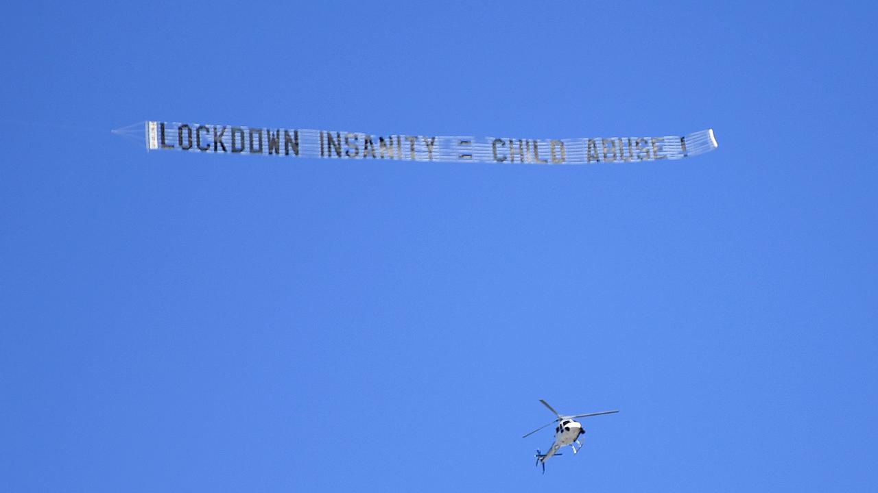 A sign reading LOCKDOWN INSANITY = CHILD ABUSE is flown over a large protest to rally for freedom of speech, movement, choice, assembly, and Health in Brisbane. Picture: NCA NewsWire / Dan Peled