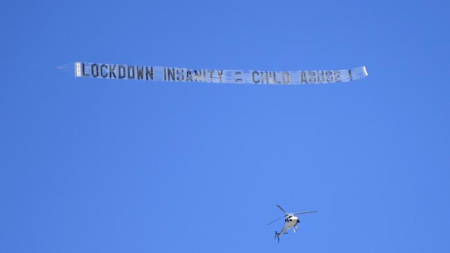 A sign reading LOCKDOWN INSANITY = CHILD ABUSE is flown over a large protest to rally for freedom of speech, movement, choice, assembly, and Health in Brisbane. Picture: NCA NewsWire / Dan Peled