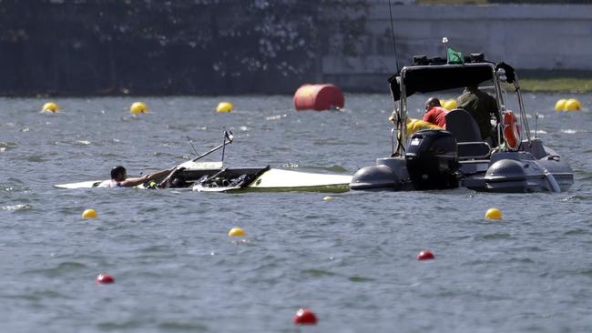 Milos Vasic and Nenad Bedik, of Serbia, are helped out of the water after capsizing while competing in the men's pair heat.