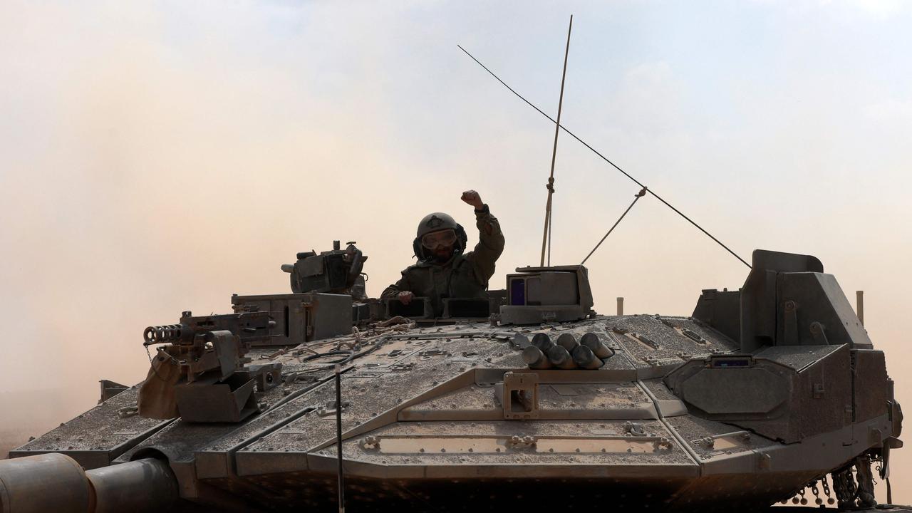 An Israeli army soldier gestures while seated in the turret hatch of Merkava battle tank deploying with others along the border with the Gaza Strip. Picture: AFP