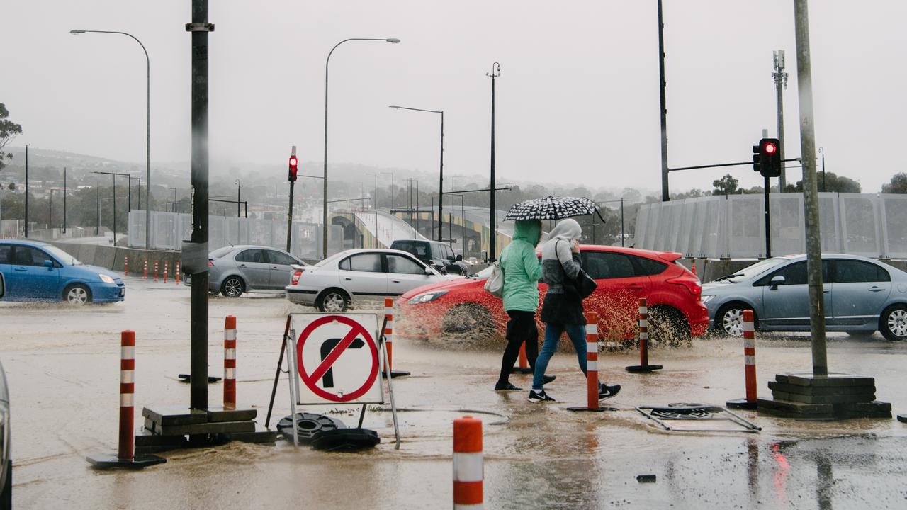 Two pedestrians walk through heavy rain and roadworks along Main South Road. Picture: Morgan Sette