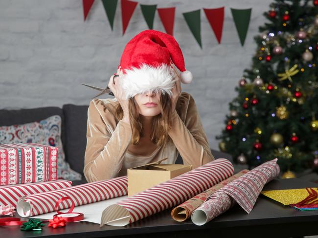 Depressed frustrated woman wrapping Christmas gift boxes, winter holiday stress concept