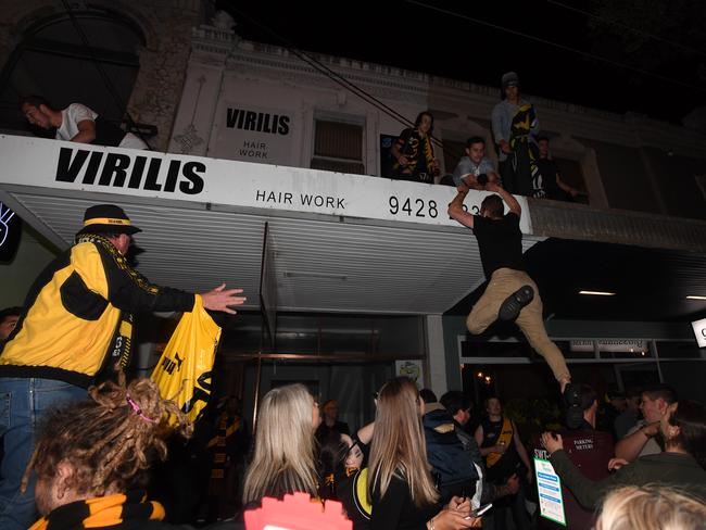 Tigers supporters climb on to a roof while celebrating along Swan St. Picture: AAP/James Ross