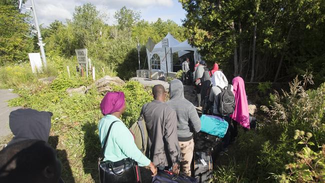 A long line of asylum-seekers wait to illegally cross the Canada/US border near Champlain, New York on August 6. The number of people illegally crossing the border has exploded.