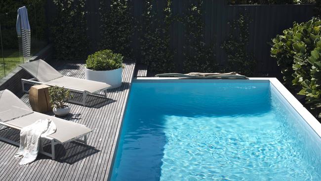 The relaxed pool deck area is surrounded by lush green walls of plantings.