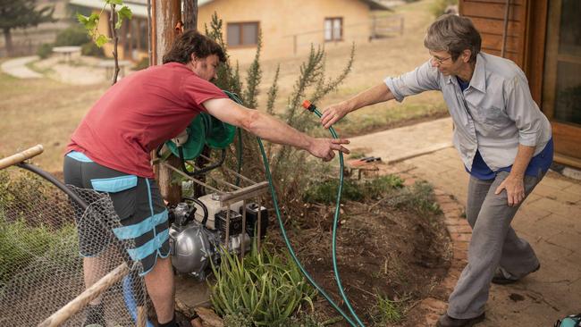 Nambugga resident Dave Hargreaves, left, installs a sprinkler system for Jenny Spinks at her home in Bega. Picture: Sean Davey.