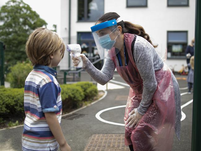 LONDON, ENGLAND - JUNE 04: A member of staff wearing personal protective equipment (PPE) takes a child's temperature at the Harris Academy's Shortland's school on June 04, 2020 in London, England. As part of Covid-19 lockdown measures, Harris Academy schools have taught smaller pods of students, to help maintain social distancing measures. With restrictions now lifting and the Government encouraging schools to re-open, the school staff has been working to find the best way to provide extra spaces while still retaining the correct social distancing measures and cleanliness requirements. This week, some schools across England reopened for some students, with children in reception, Year 1 and Year 6 allowed to return first. (Photo by Dan Kitwood/Getty Images)