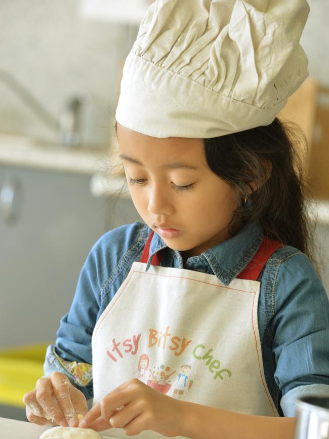 Qiara, 5, cooking up a storm as part of a new school holiday program. Picture: Kris Reichl