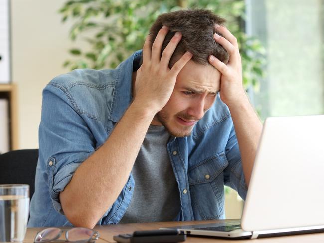 A stressed man at his computer after just realising he has been scammed. Picture: iStock.