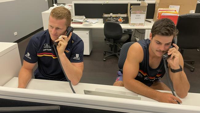 Crows players Reilly O’Brien and Darcy Fogarty take to the phones to call affected ticket holders. Picture: Adelaide Crows/Twitter