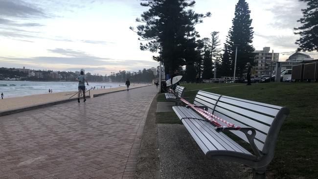 Benches along Manly seafront taped up due to COVID-19 social distancing rules. Picture: Julie Cross