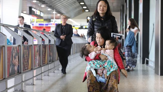 Travelling nurse Tshewang Choden pushes mum Bhumchu Zangmo in a wheelchair as she holds Nima and Dawa arriving into Melbourne. Picture: Alex Coppel