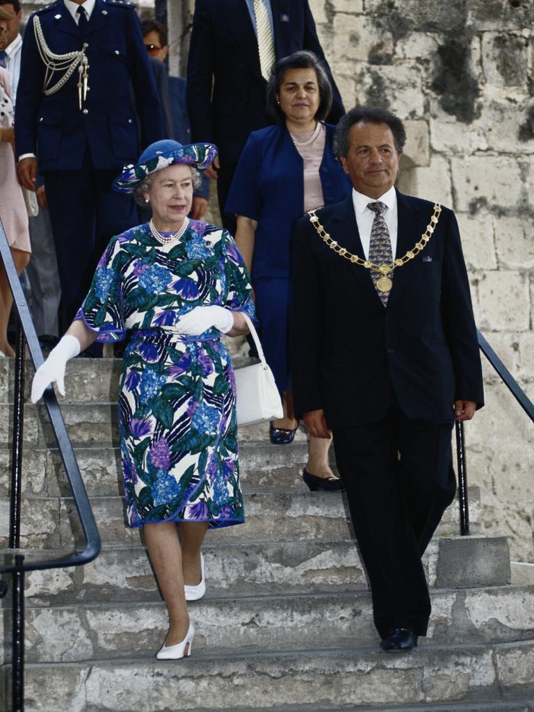 Queen Elizabeth II, wearing a blue multi-coloured dress designed by John Anderson, and a hat by milliner Philip Somerville, on a walkabout with local dignitaries during a visit to Cyprus, in October, 1993. Picture: Tim Graham/Getty Images