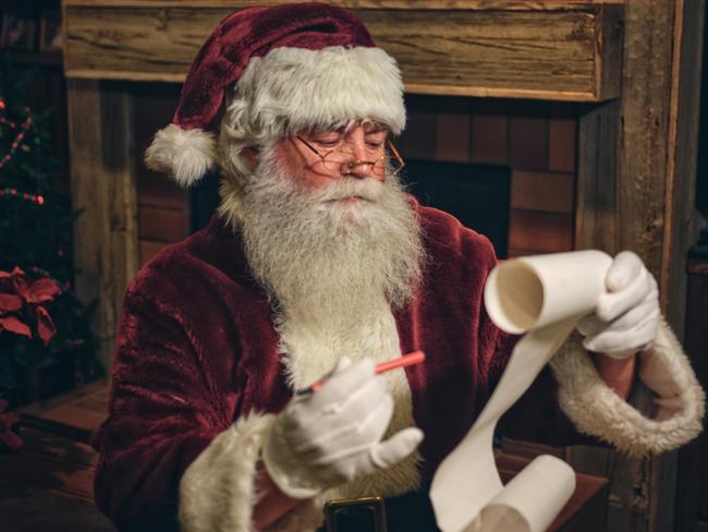 Santa Claus in a home, reading a Christmas list. istock image