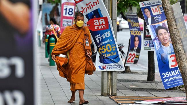 A Buddhist monk makes his way past campaign posters in Bangkok this week. Picture: AFP