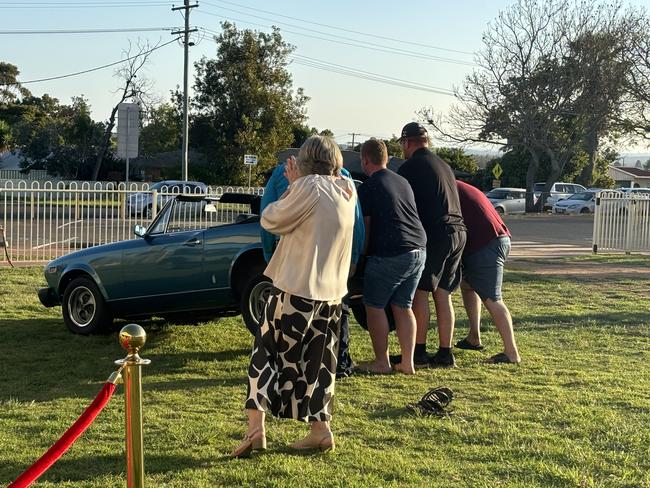 Members of the crowd help out when a car breaks down on the red carpet.