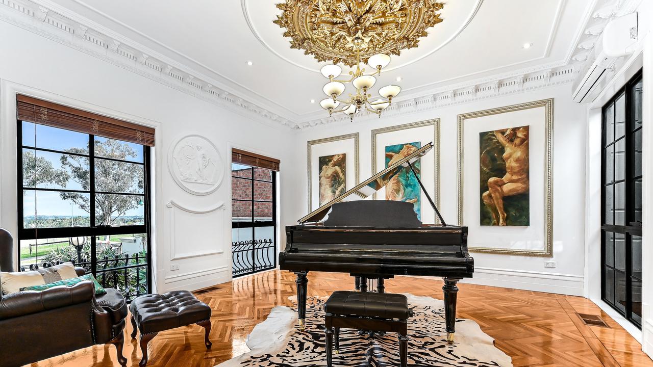 Artwork, a piano, rose gold ceiling cornice and chandelier combine to impress.