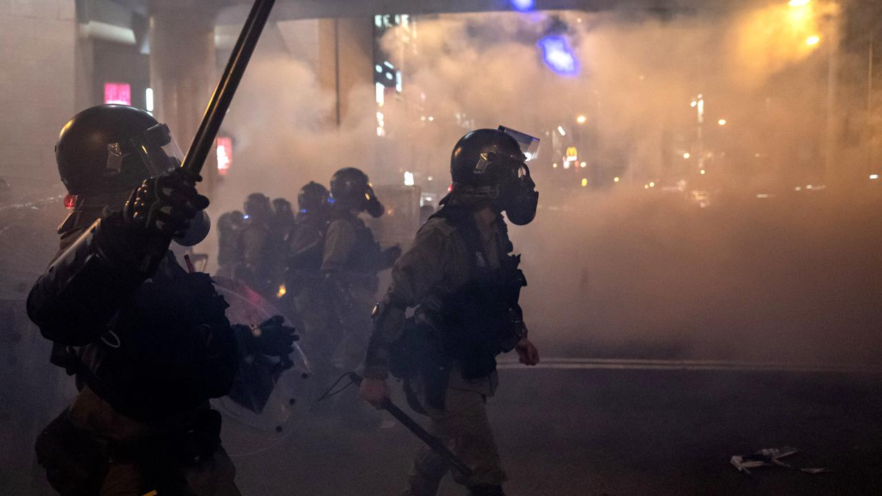 Riot police charge toward protesters in a fume of tear gas on an express way at Causeway Bay on Sunday night. Picture: Getty Images