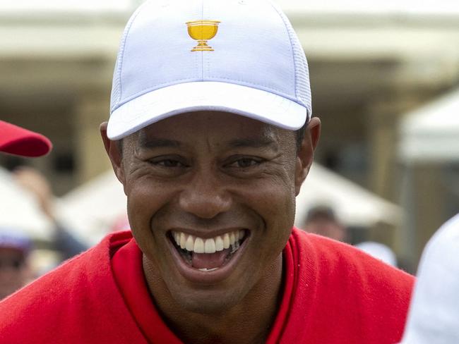 (FILES) In this file photo taken on December 15, 2019 US team captain Tiger Woods (C), US player Zach Johnson (R) and caddy Joe LaCava (L) speak after Woods won his match on the final day of the Presidents Cup golf tournament in Melbourne on December 15, 2019. - Tiger Woods, a 15-time major champion recovering from injuries suffered last month in a car crash, is making a comeback in golfing videogames, announcing a new deal on March 16, 2021 with 2K. The company and Woods have agreed upon a long-term exclusive partnership and 2K announced it has struck a deal to obtain HB Studios, developers of the PGA Tour 2K21 as well as The Golf Club franchise. (Photo by SIMON BAKER / AFP) / -- IMAGE RESTRICTED TO EDITORIAL USE - STRICTLY NO COMMERCIAL USE --