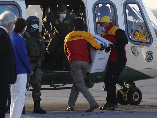 SANTIAGO, CHILE - DECEMBER 24: President of Chile Sebastian PiÃÂ±era observes workers of DHL who carry the first batch of 10,000 doses of Pfizer/BioNTech vaccine for COVID-19 to a helicopter to be taken to Estadio Nacional at Arturo Merino BenÃÂ­tez on December 24, 2020 in Santiago, Chile.  (Photo by Marcelo Hernandez/Getty Images)