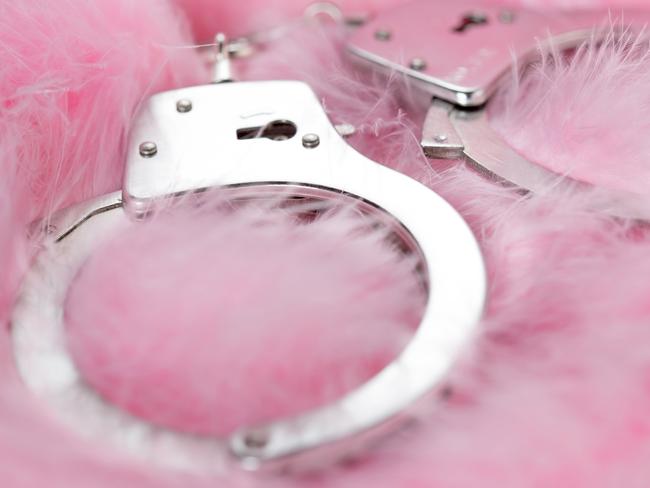 handcuffs in a background of pink feathers