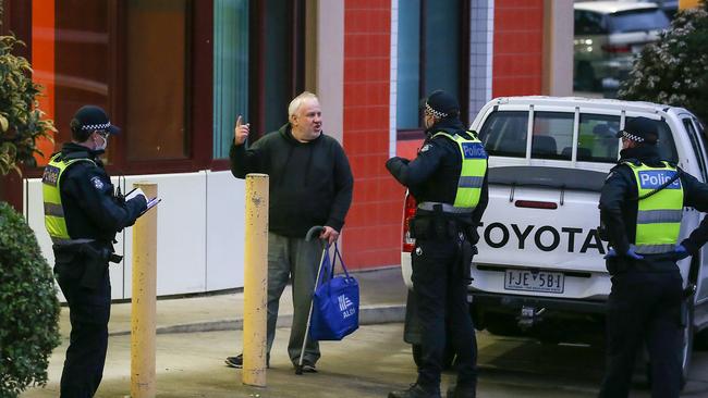 Police talk to a resident outside the North Melbourne towers. Picture: Ian Currie